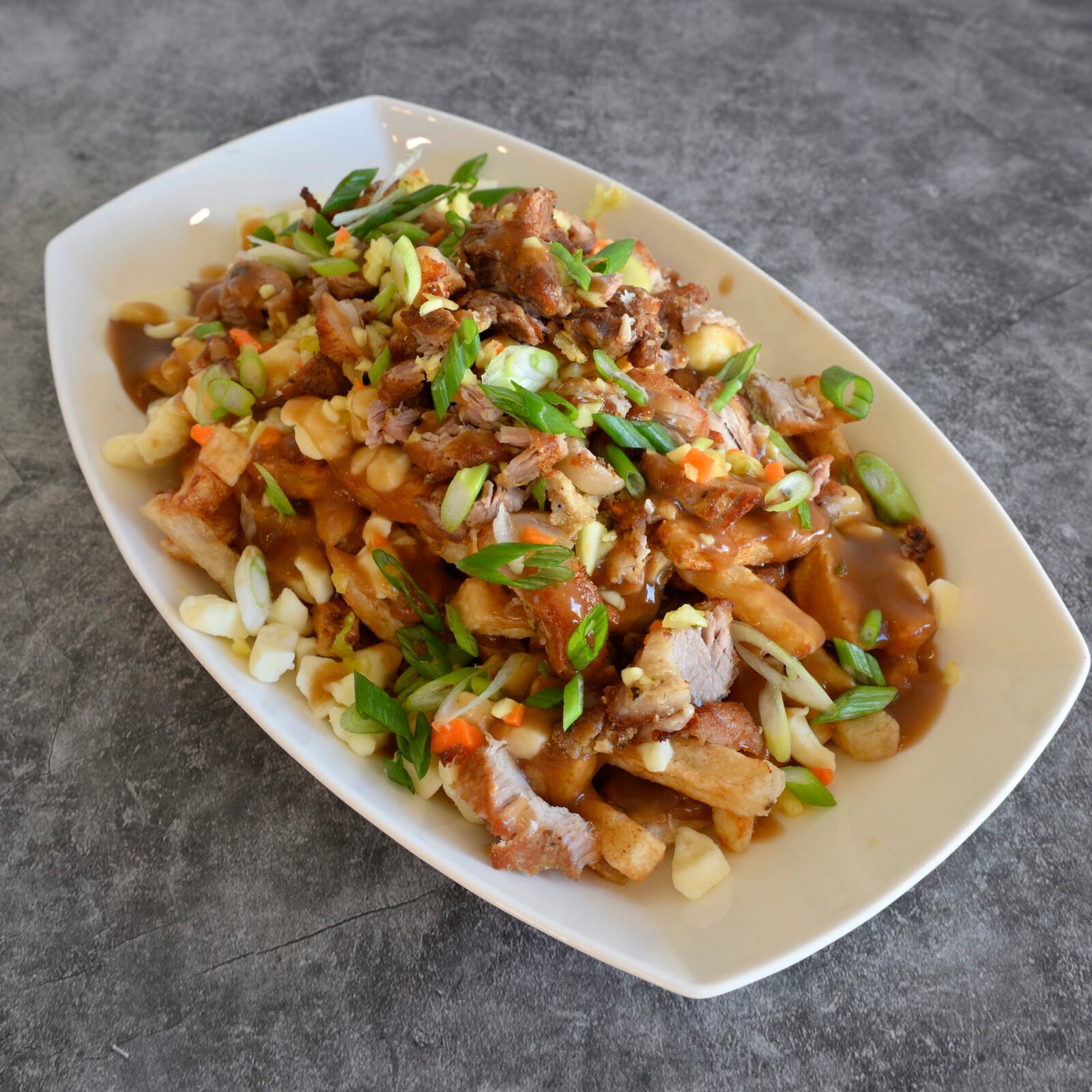 Poutine fusion garnie de viande et d’oignons verts chez Racine Créole